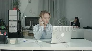 年轻的<strong>办公</strong>室秘书在手提电脑和<strong>接电话</strong>